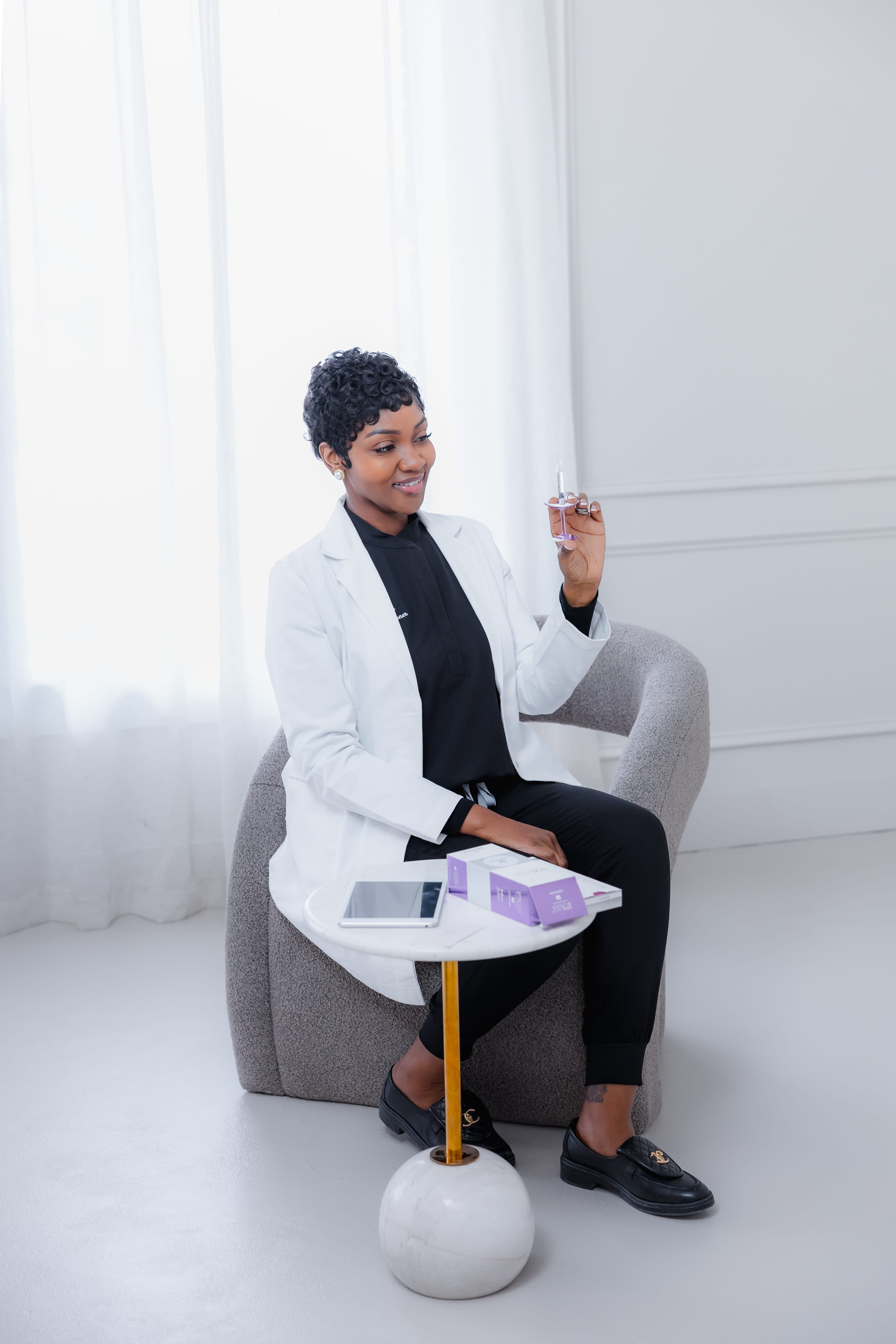 Cleo R. in her white coat, seated with an aesthetic syringe